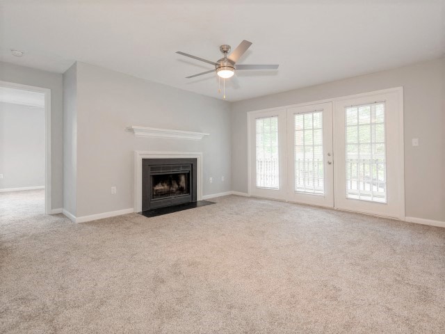 an empty living room with a fireplace and a ceiling fan