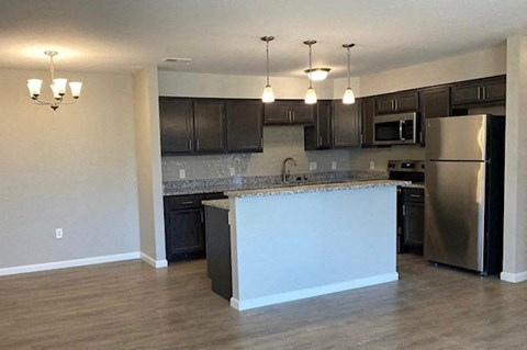 an empty kitchen with an island and stainless steel refrigerator