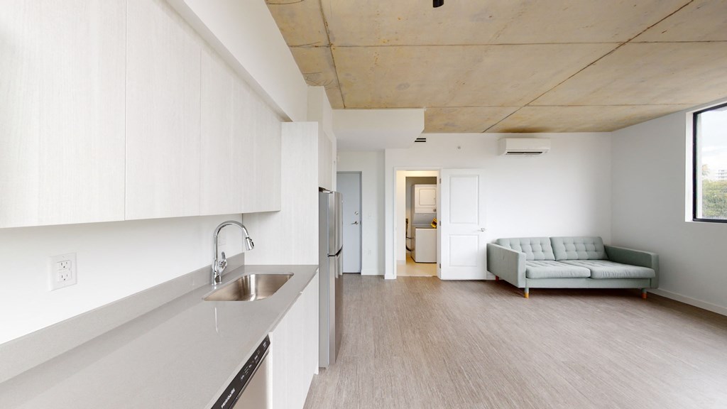 a kitchen and living room with white cabinets and a sink