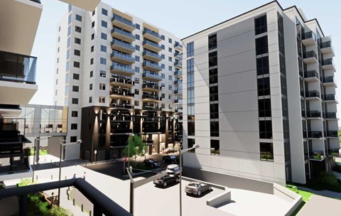 A modern apartment complex with cars parked in the driveway.