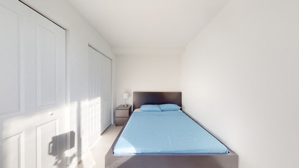 a white bedroom with a blue bed and white walls