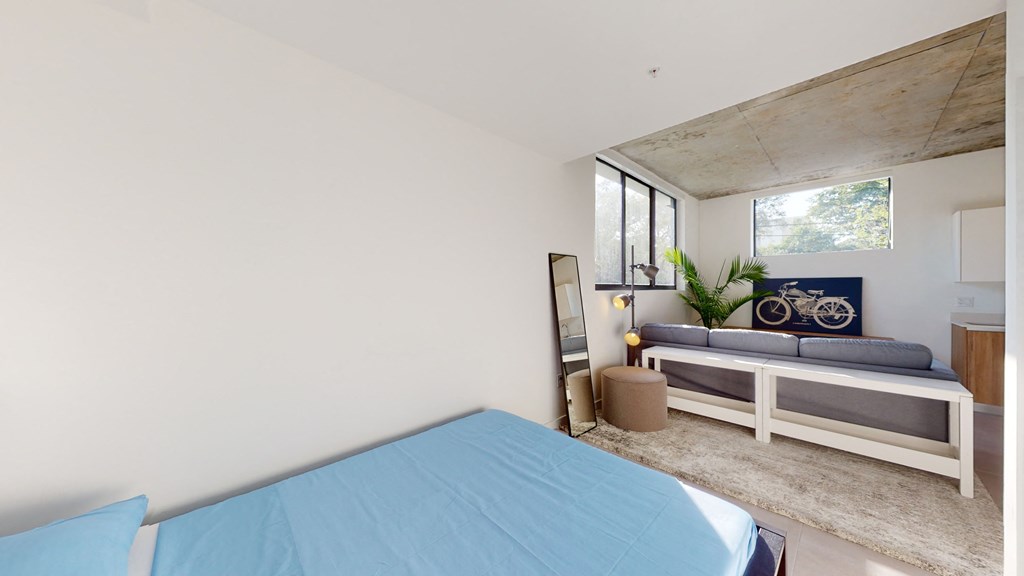 a bedroom with a bed and a couch in front of a window