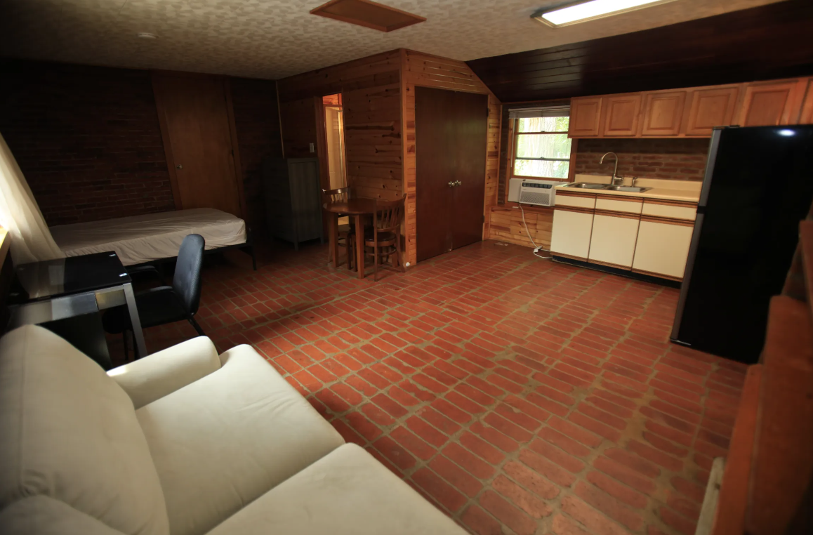 the living room of a cabin with a couch and a kitchen
