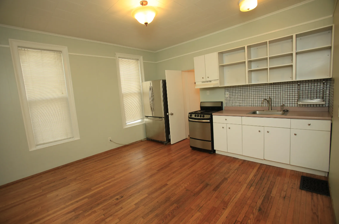 a kitchen with a wooden floor and white cabinets