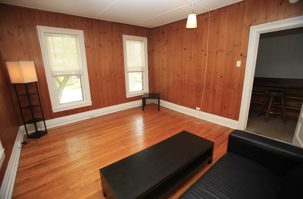 a living room with wood paneling and a black couch