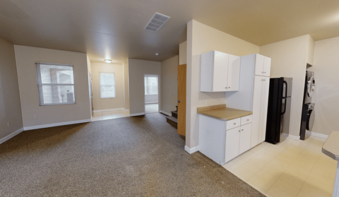 A kitchen area with white cabinets and a black refrigerator.