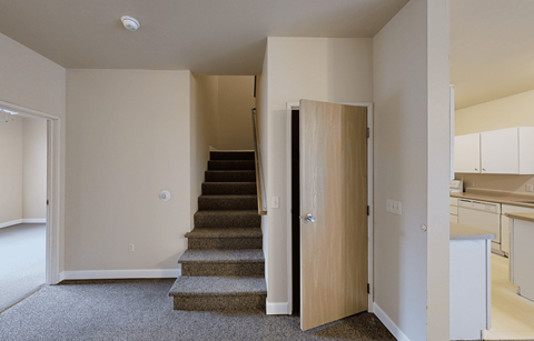 A staircase with a carpeted runner leads up to a second floor.