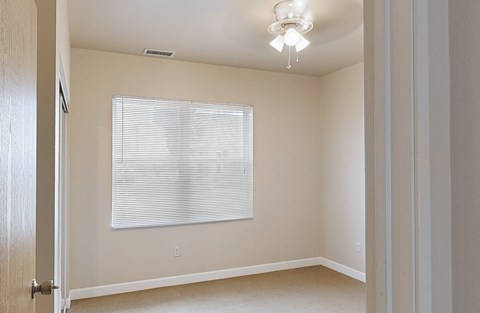 A room with a window covered by white blinds.