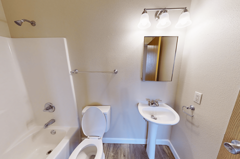 A white toilet sits next to a white sink in a small bathroom.