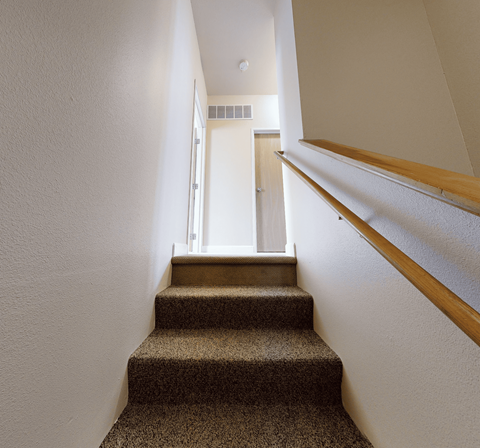 A staircase with a carpeted runner and wooden handrails.