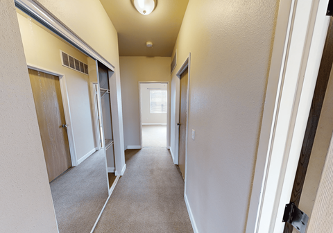 A hallway with carpeted floors and white walls.
