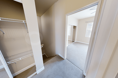 A small, empty room with a white door and a white fridge.