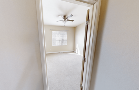 A white room with a ceiling fan and a window.