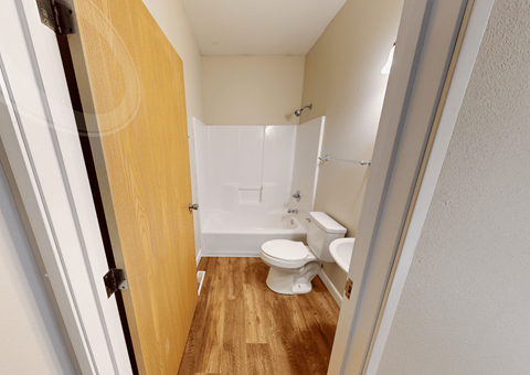 A white toilet sits in a small bathroom with a wooden door.