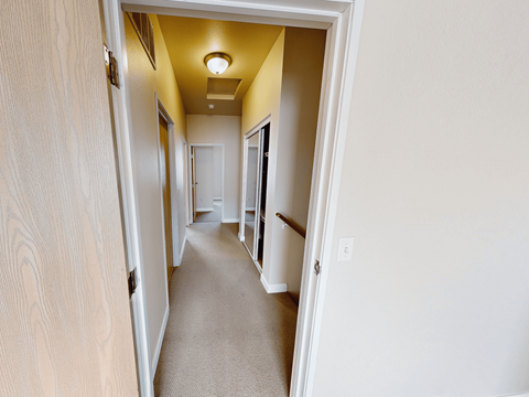 A hallway with a carpeted floor and white walls.