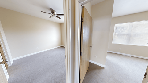 A room with a ceiling fan and carpeted floor.