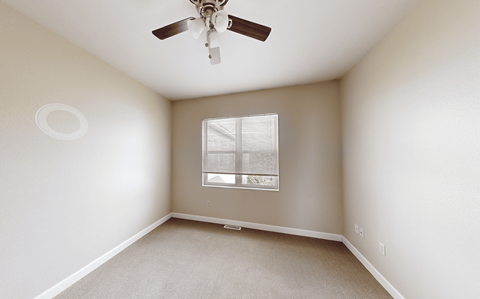A room with a ceiling fan and a window with blinds.