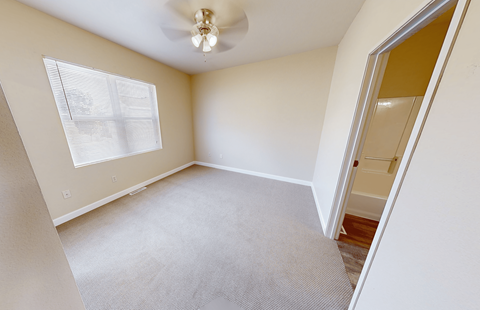 A room with a carpeted floor and a ceiling fan.