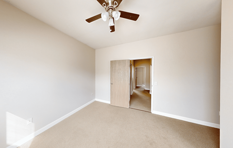 A room with a ceiling fan and carpeted floor.