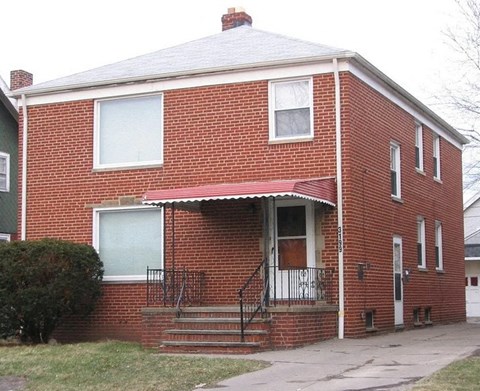 A red brick house with a white door and windows.