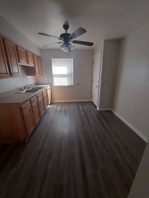 A kitchen with wooden cabinets and a ceiling fan.