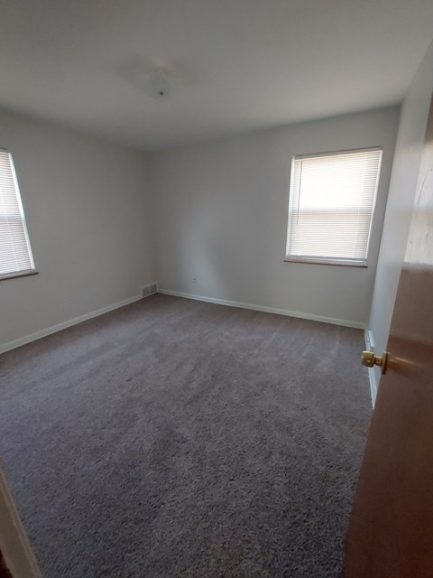 A room with a carpeted floor and a window with blinds.