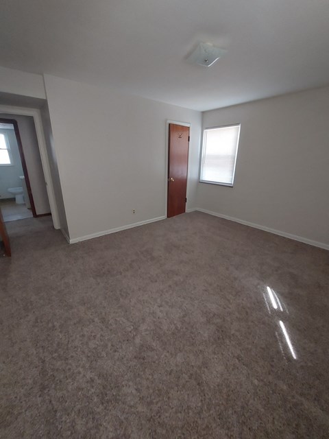 A room with a carpeted floor and a door.