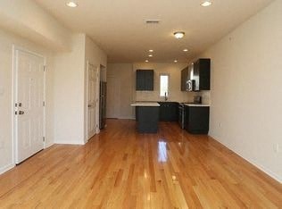 an empty living room and kitchen with wood floors