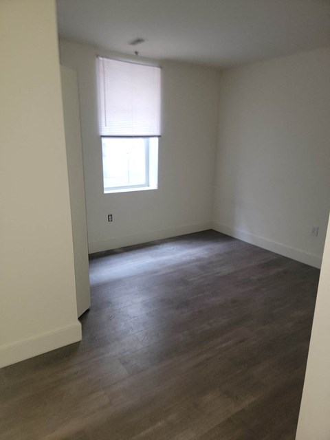 an empty living room with wood floors and a window