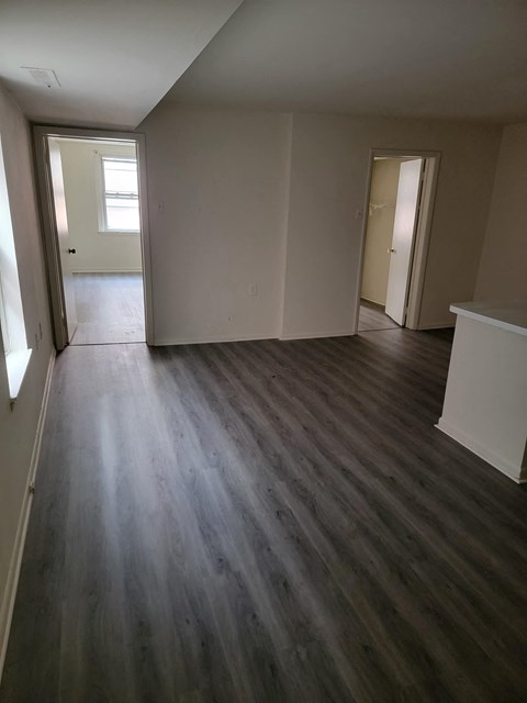 an empty living room with wooden floors and white walls