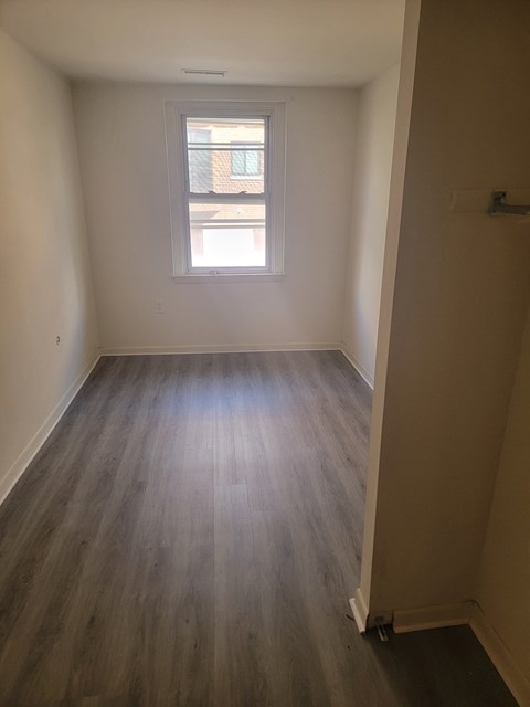 an empty room with wooden floors and a window