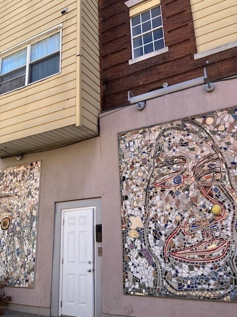 a building with a mosaic mural and a white door