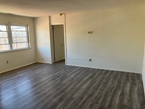 an empty living room with wooden floors and a window