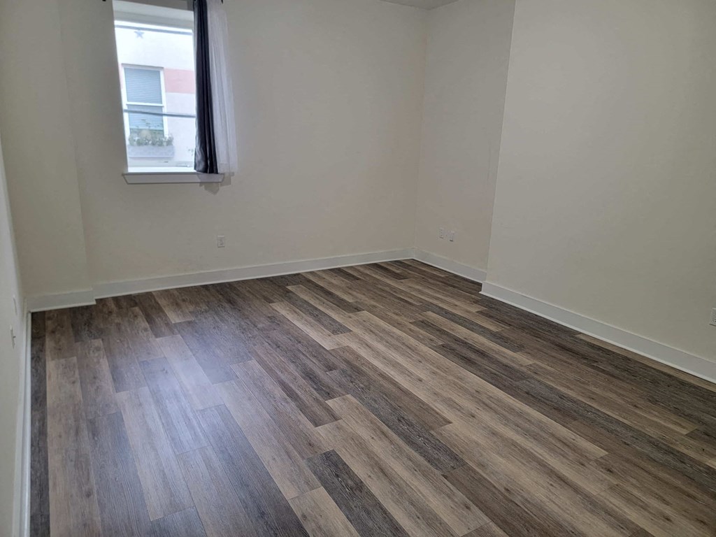 a bedroom with wood flooring and a window