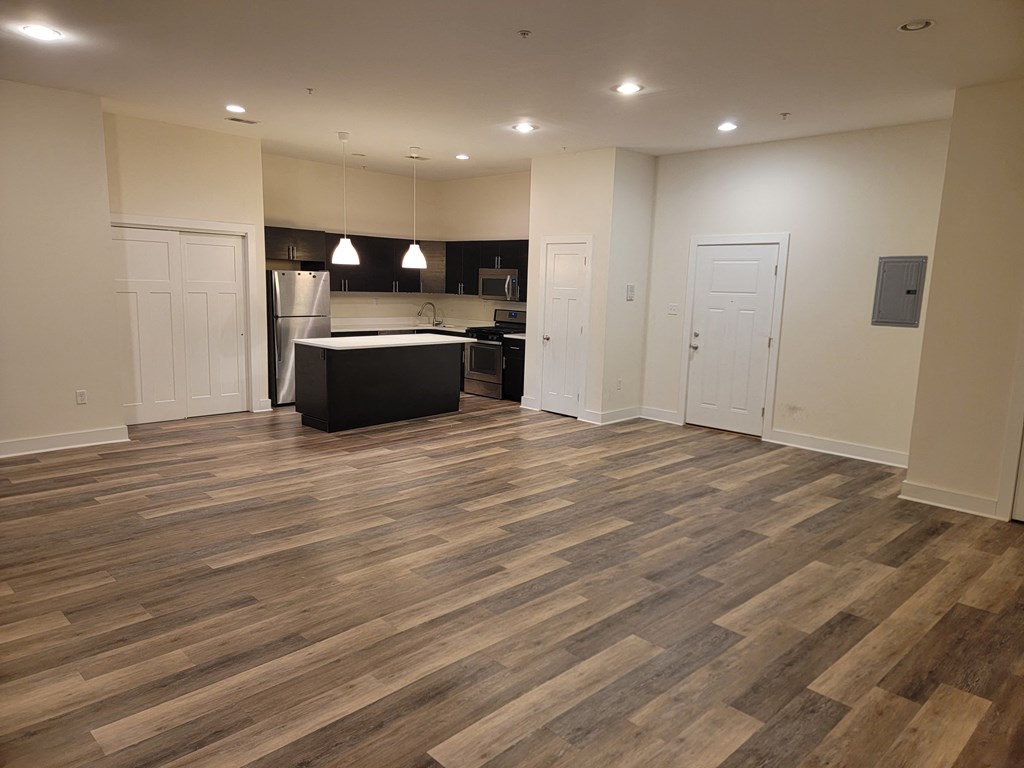 a kitchen and living room with wood flooring in an empty apartment