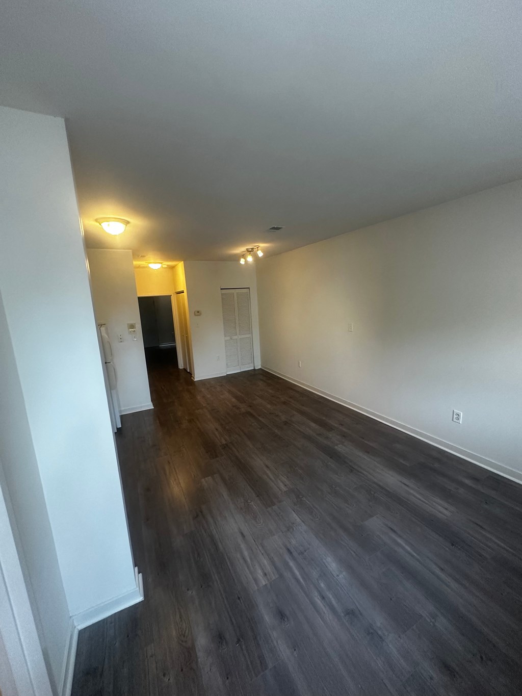 an empty living room with wooden floors and white walls