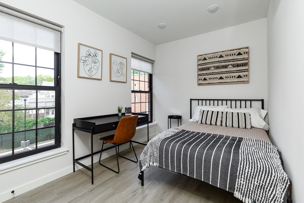 a bedroom with a bed and a desk and a large window