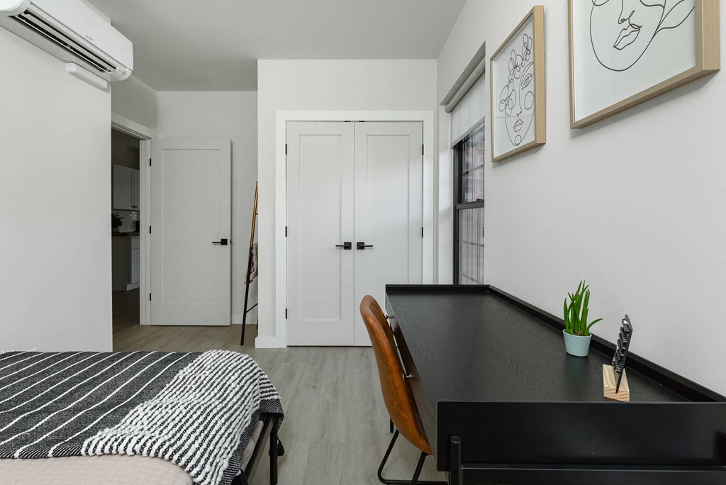 a bedroom with a black desk and a bed