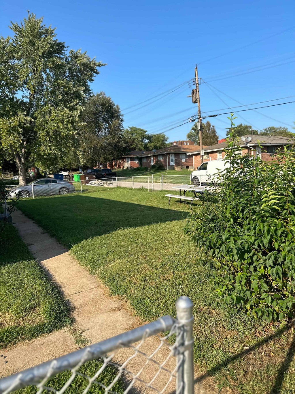 a sidewalk in the grass near a fence
