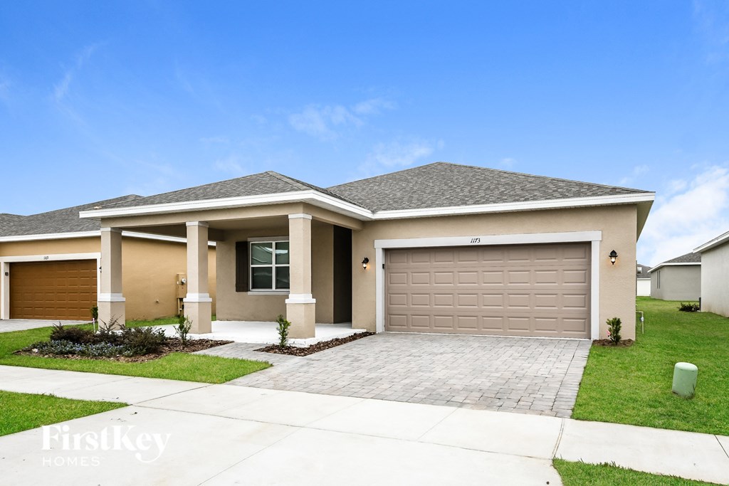 a beige house with a driveway and a garage door