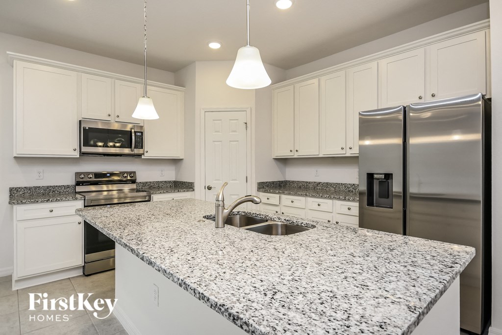 a white kitchen with granite counter tops and stainless steel appliances
