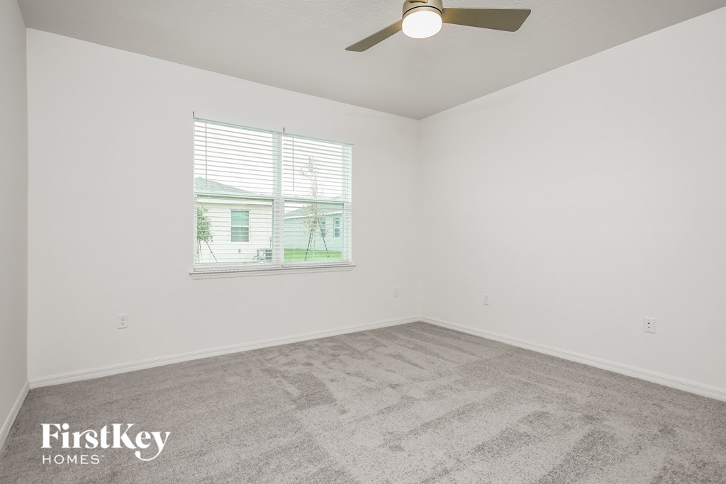 a bedroom with carpet and a window and a ceiling fan