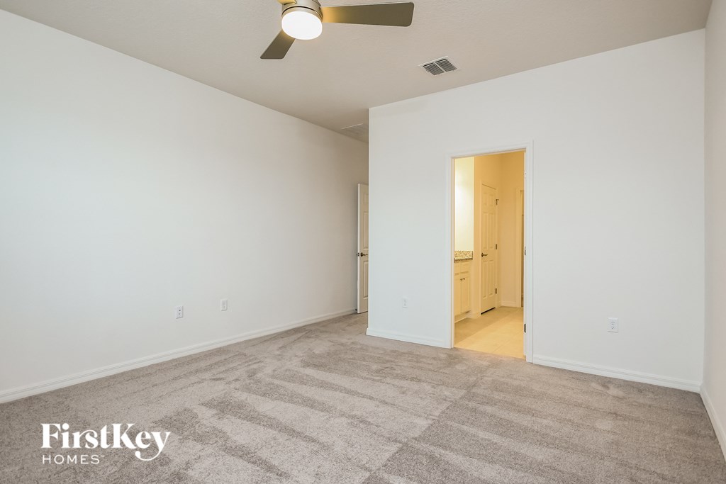 a spacious living room with white walls and a ceiling fan
