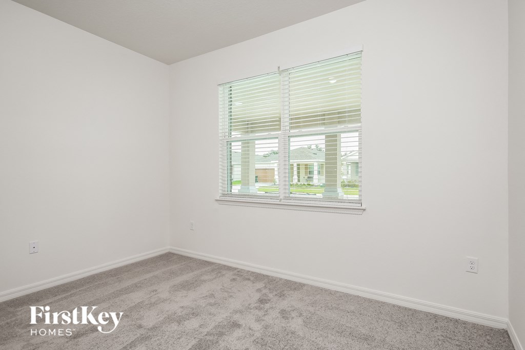 a bedroom with a large window and a carpeted floor