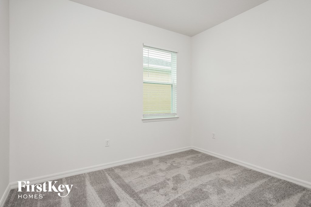 a bedroom with white walls and carpet and a window