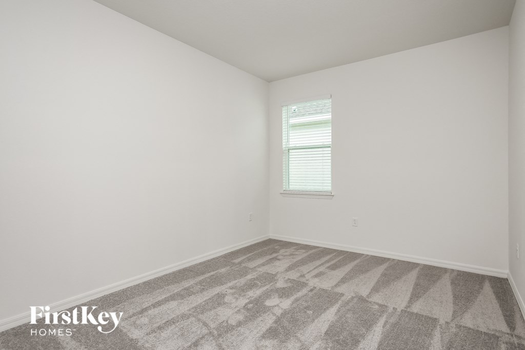 a bedroom with white walls and carpet and a window