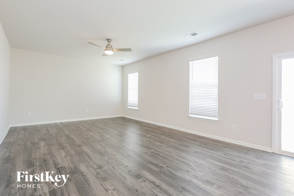 A spacious room with wooden flooring and a ceiling fan.