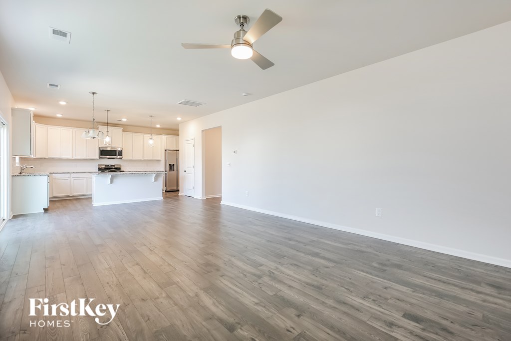 A spacious room with wooden flooring and a ceiling fan.
