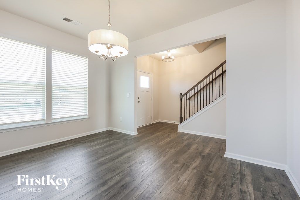 A well-lit, spacious room with a wooden floor and a staircase.