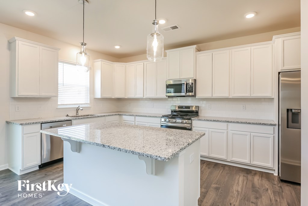 A kitchen with a granite countertop and white cabinets.